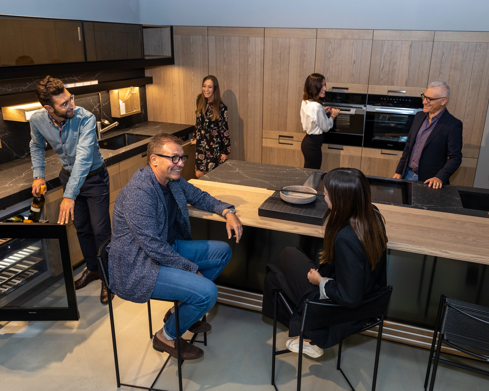 Photograph from above of an Arclinea wooden kitchen while 6 people laugh, living the environment.