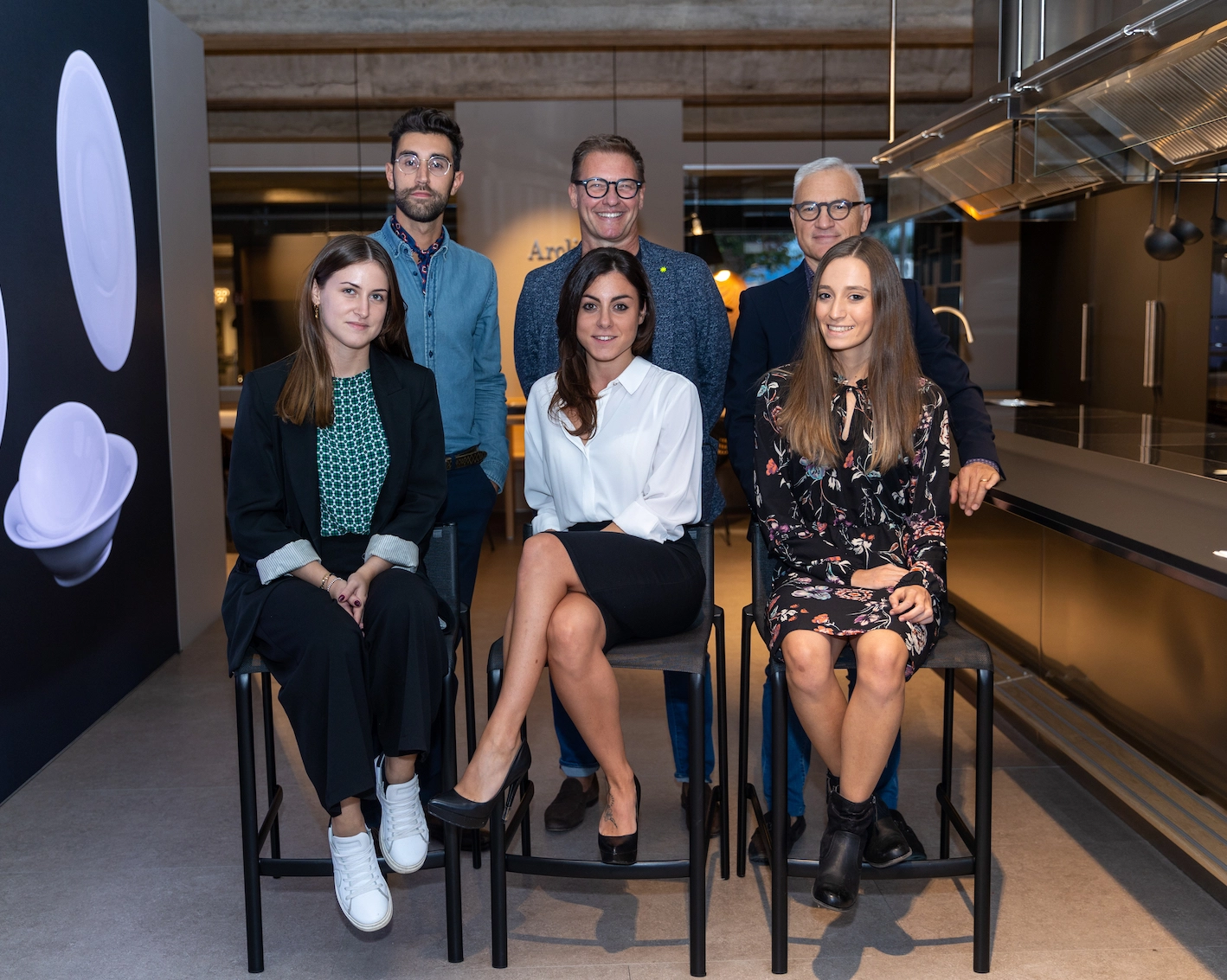 Fotografia del team di Fontana cucine e design. Sono presenti 6 persone, tre uomini in piedi e tre donne sedute su degli sgabelli davanti a loro